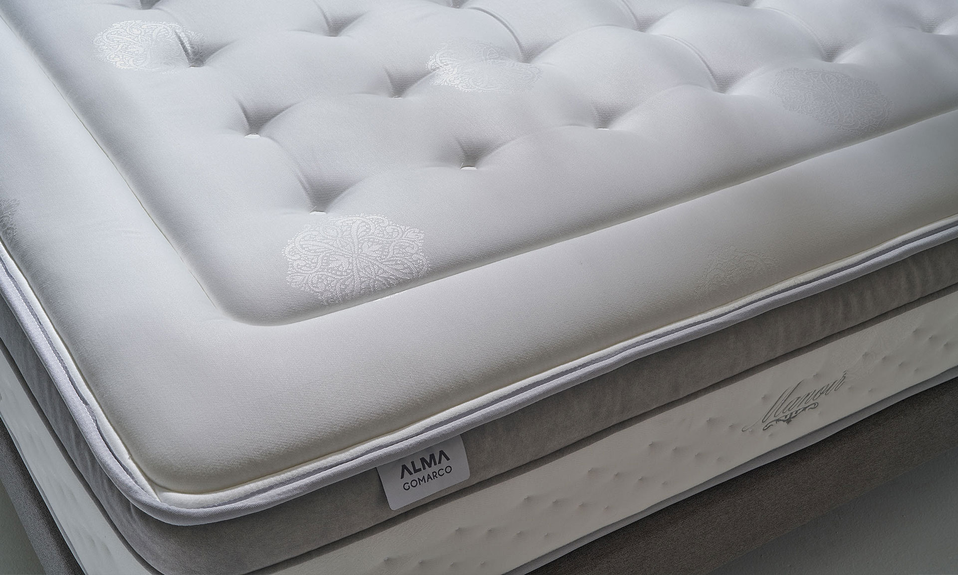 Un matelas avec Âme ressorts ensachés Springsac dont 7 zones de confort. Et tête de lit en tissu gris effet texturé.